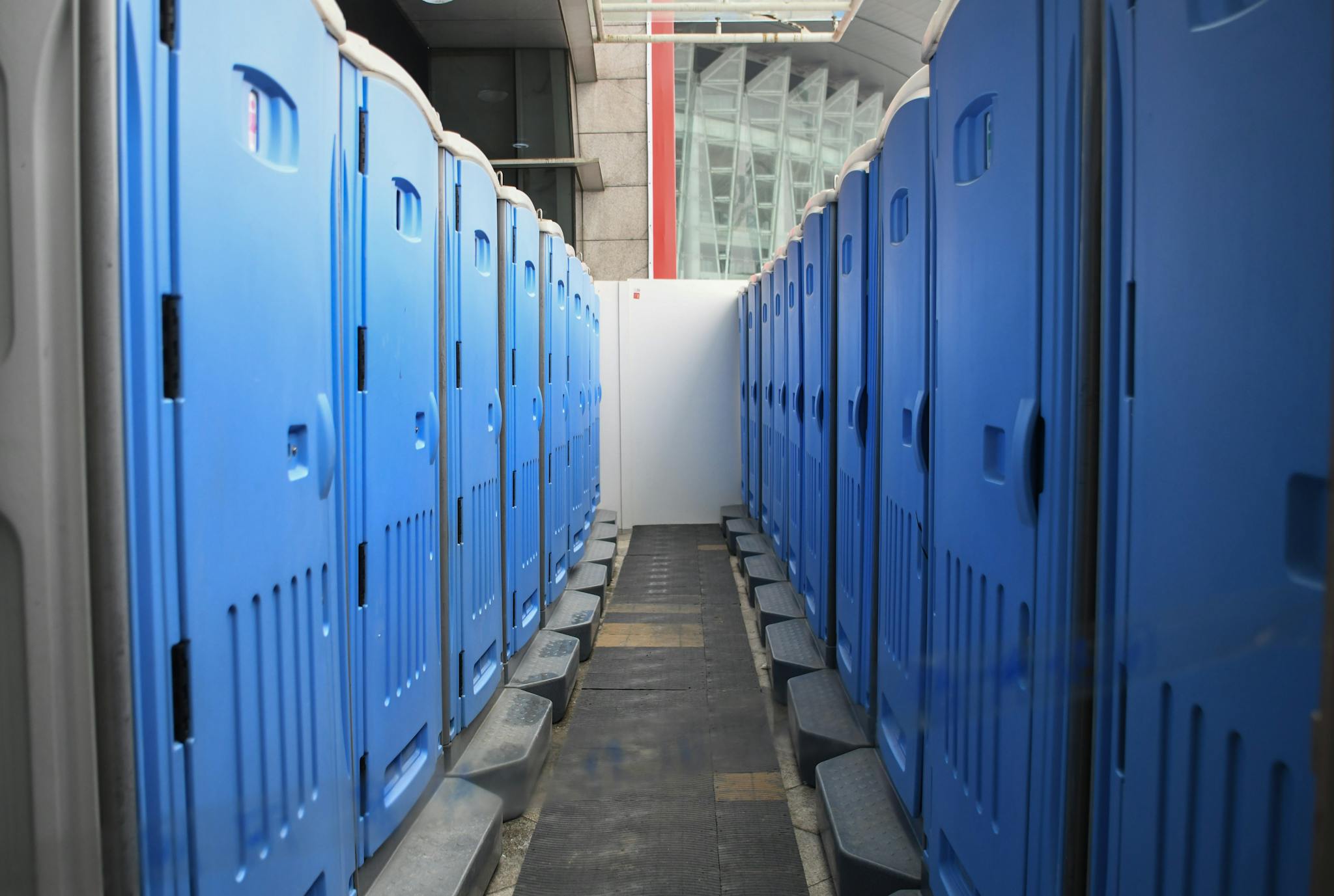 A series of blue portable toilets aligned at an outdoor construction site. portable event toilets